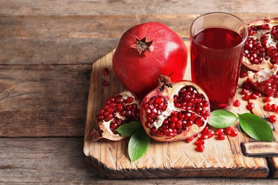 Photo of Glass of pomegranate juice and fresh fruits on wooden board, space for text