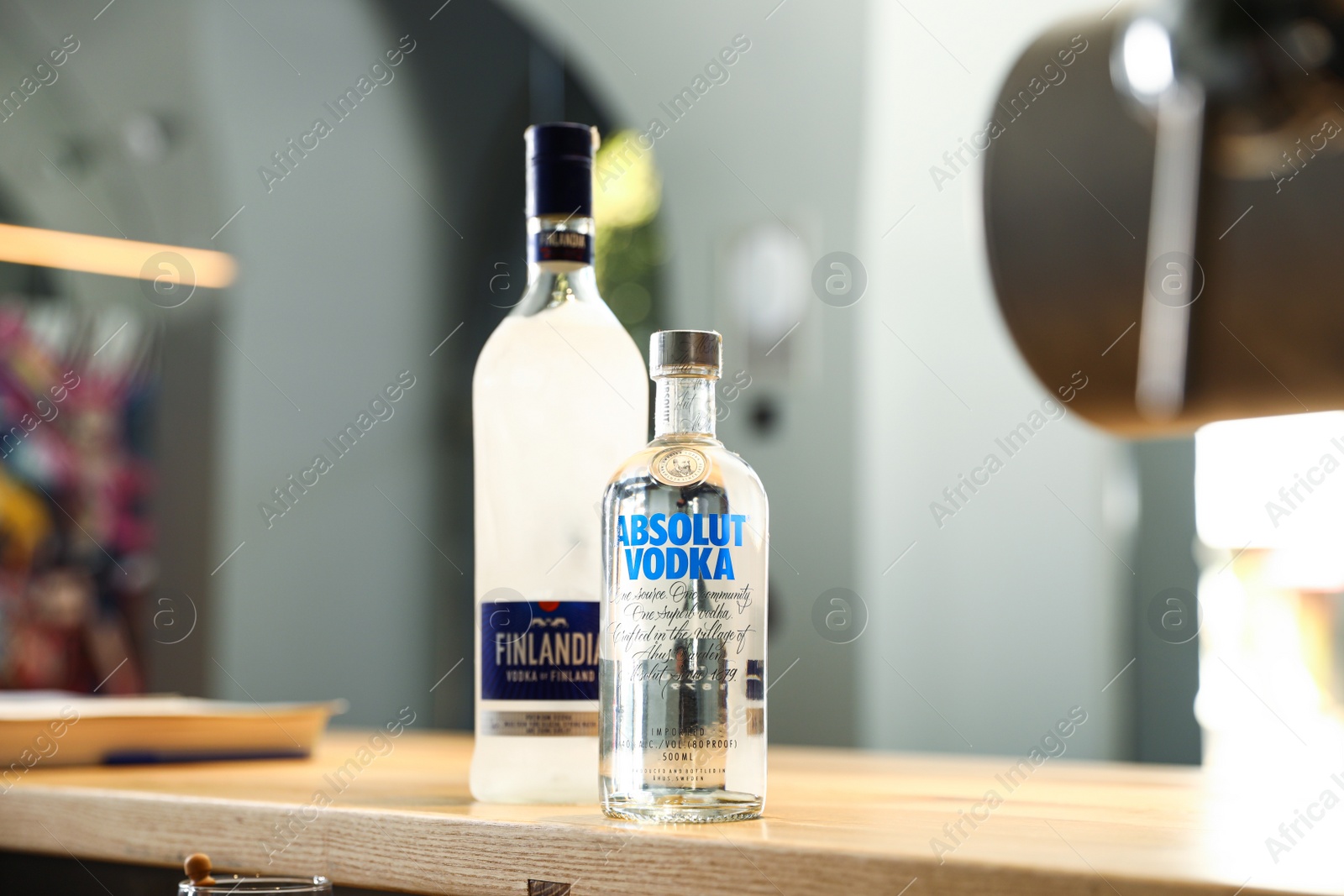 Photo of MYKOLAIV, UKRAINE - SEPTEMBER 23, 2019: Bottles of Finlandia and Absolut vodka on wooden counter in bar