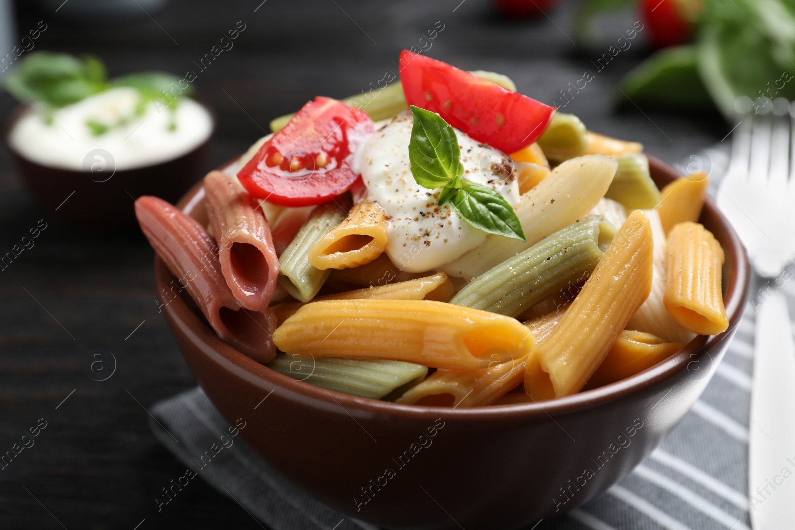 Photo of Delicious vegetable pasta with sour cream dressing on black wooden table, closeup