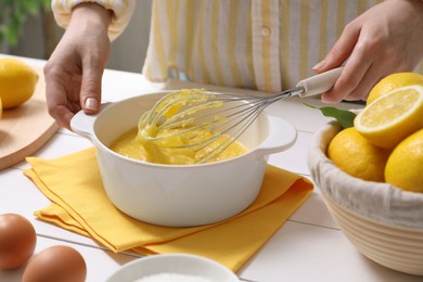 Photo of Woman cooking lemon curd at white wooden table, closeup