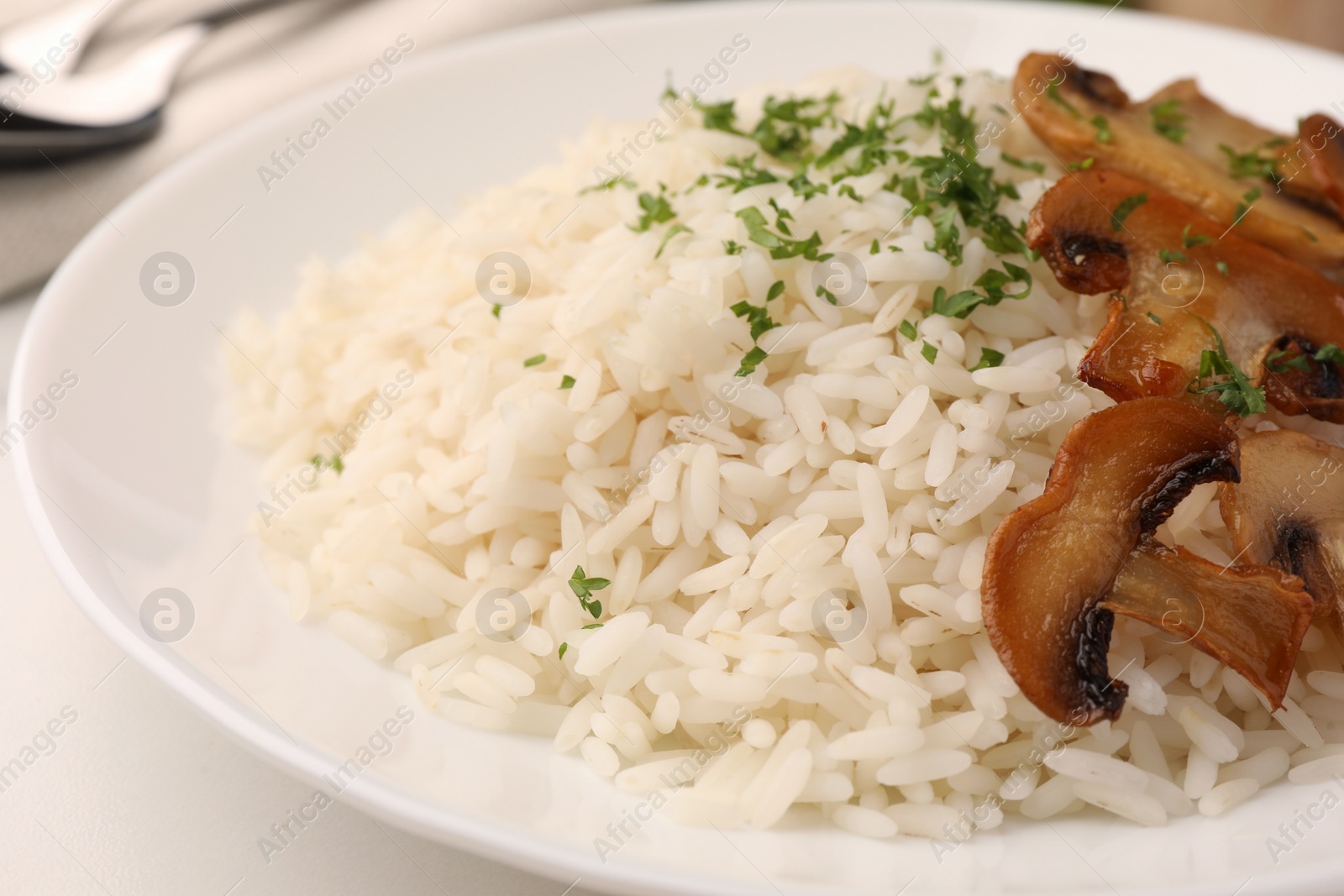 Photo of Delicious rice with parsley and mushrooms on white table, closeup