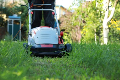 Photo of Man cutting grass with lawn mower in garden, closeup. Space for text