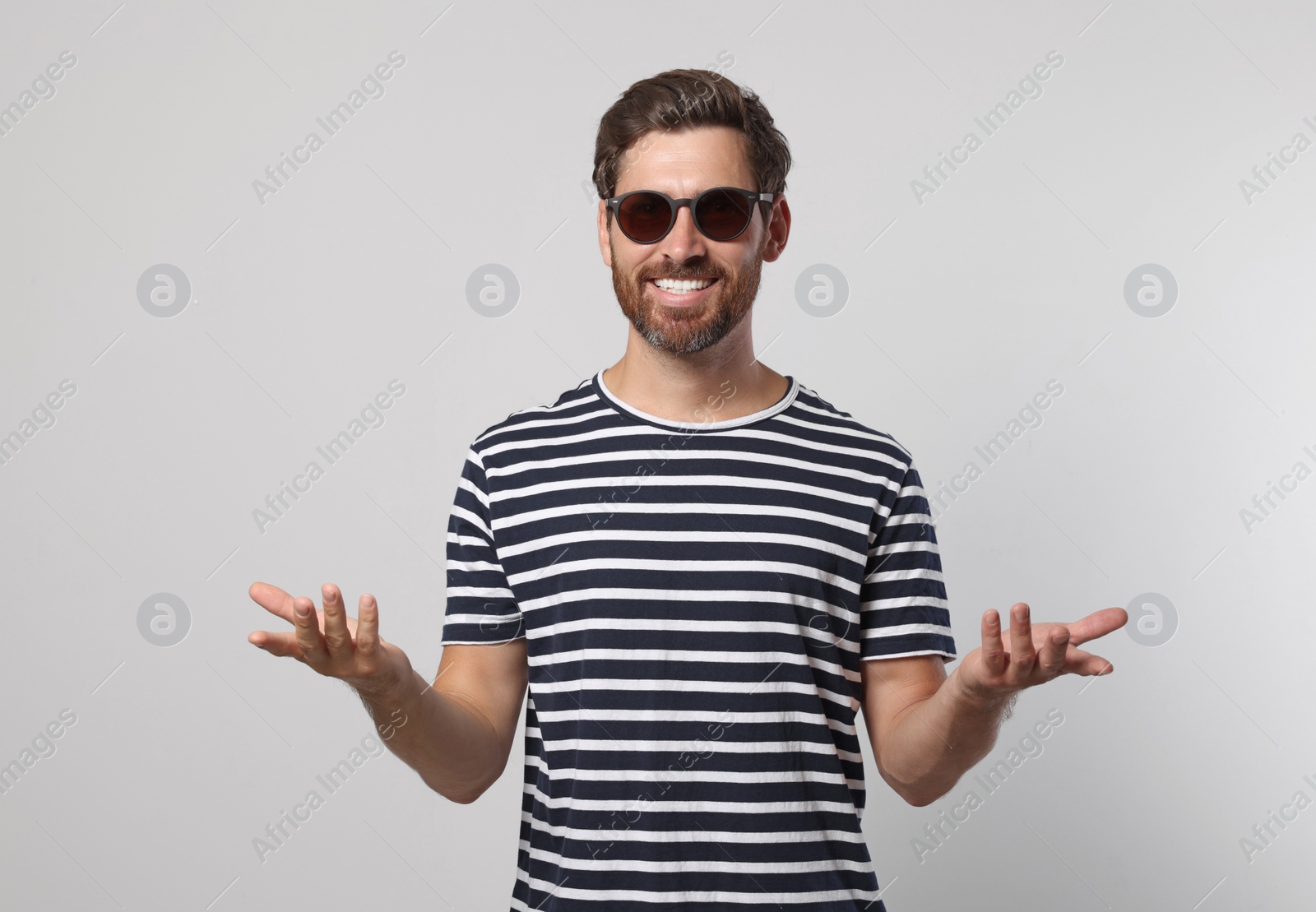 Photo of Portrait of smiling bearded man with stylish sunglasses on grey background