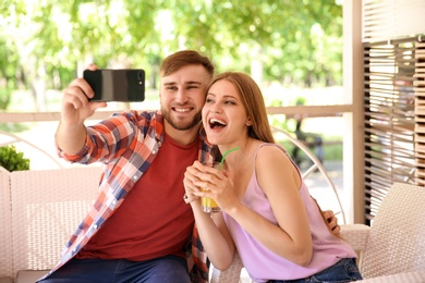 Photo of Happy young couple taking selfie in cafe on spring day