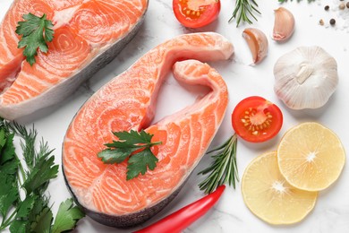 Photo of Fresh salmon and ingredients for marinade on white marble table, flat lay