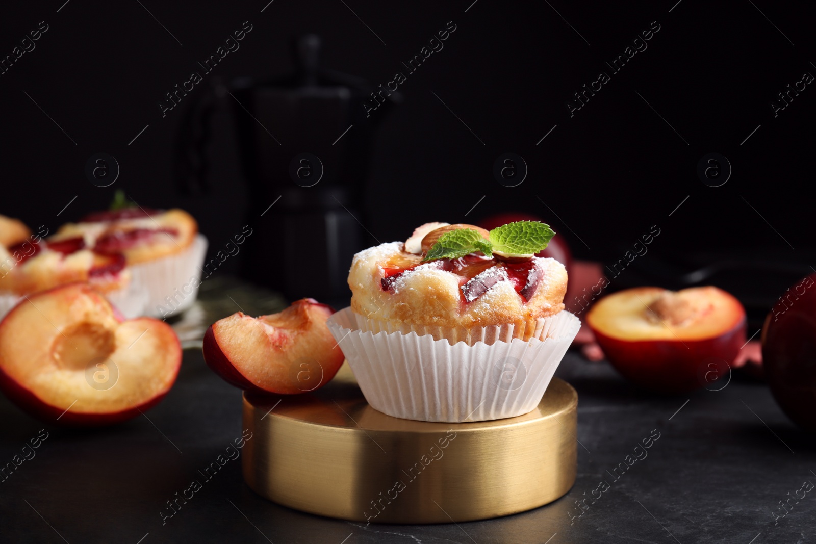 Photo of Delicious cupcakes with plums on black table, closeup