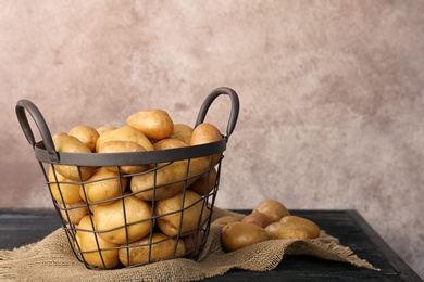 Basket with fresh organic potatoes and space for text on color background