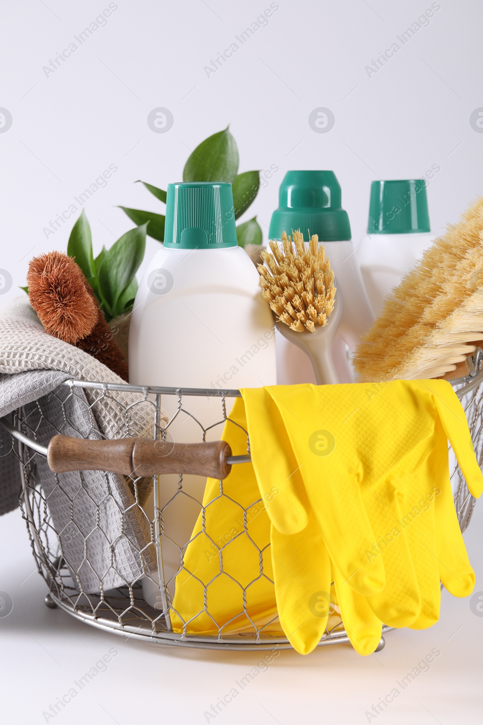 Photo of Set of different cleaning supplies in basket on white background