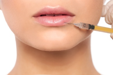 Photo of Young woman getting lips injection on white background, closeup. Cosmetic surgery