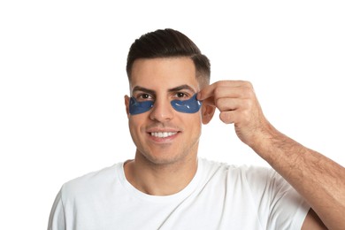 Photo of Man applying blue under eye patch on white background