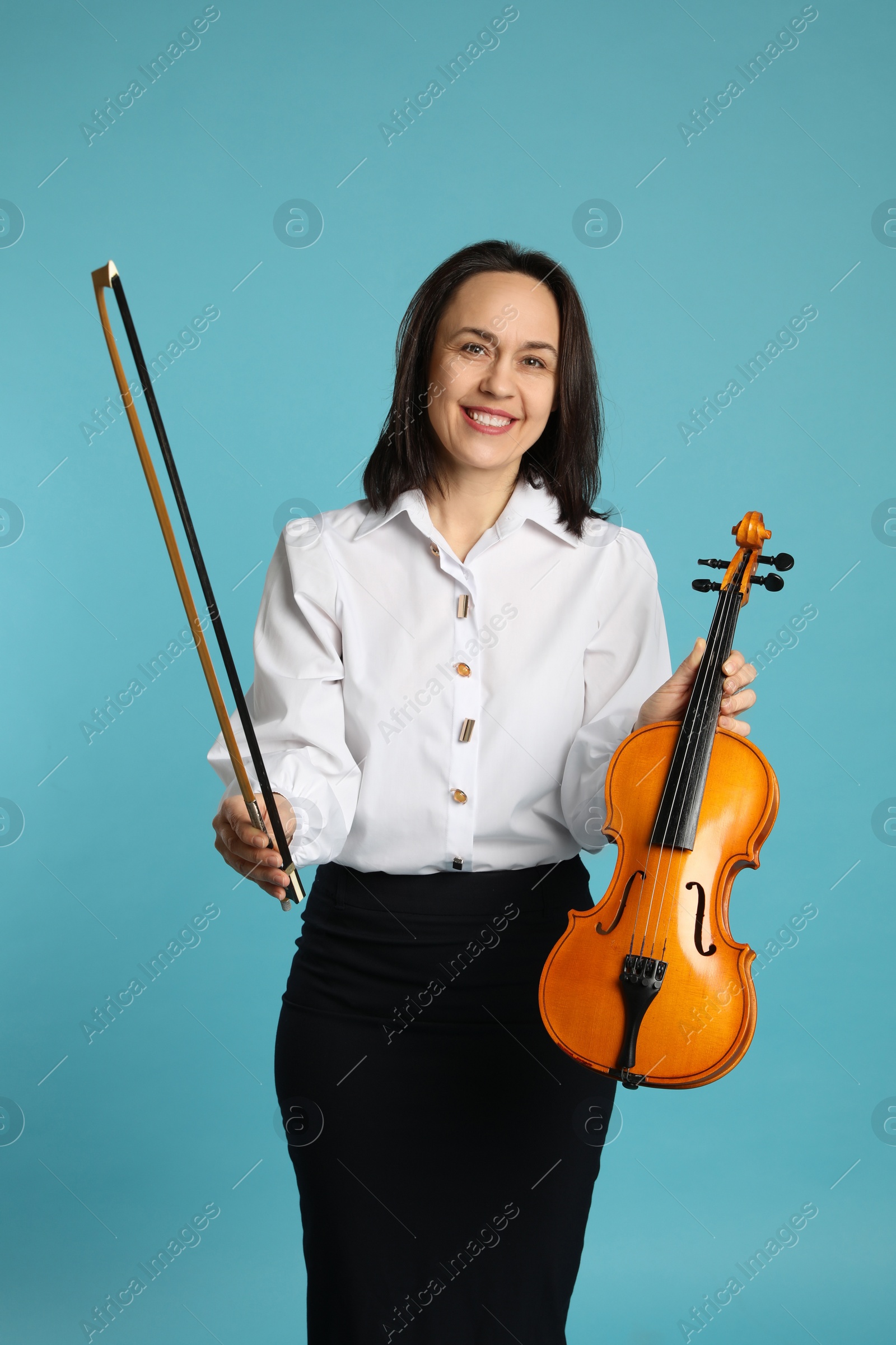 Photo of Music teacher with violin and bow on turquoise background