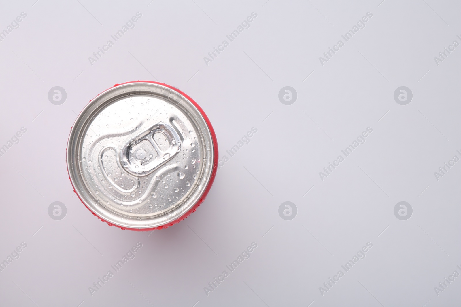 Photo of Energy drink in wet can on light grey background, top view. Space for text