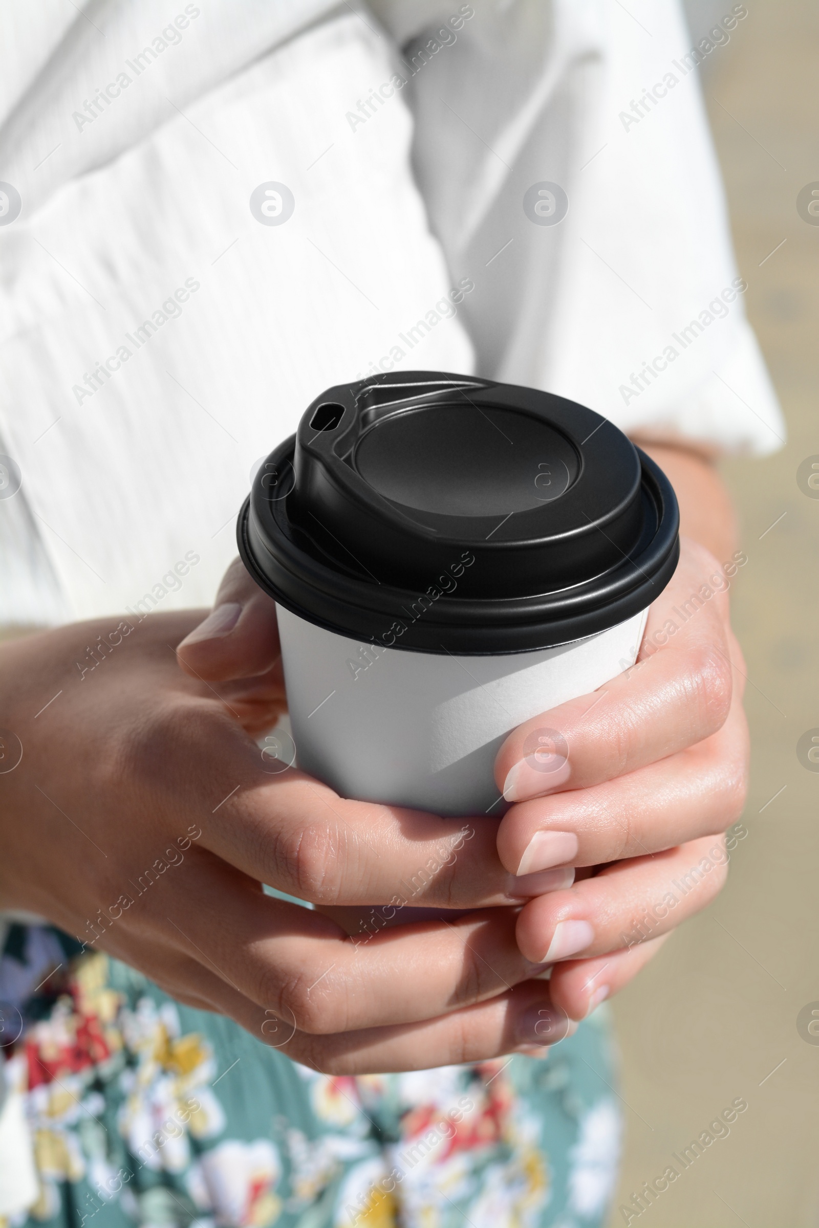 Photo of Woman holding takeaway coffee cup outdoors, closeup