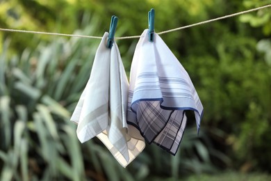 Photo of Different handkerchiefs hanging on rope against blurred background