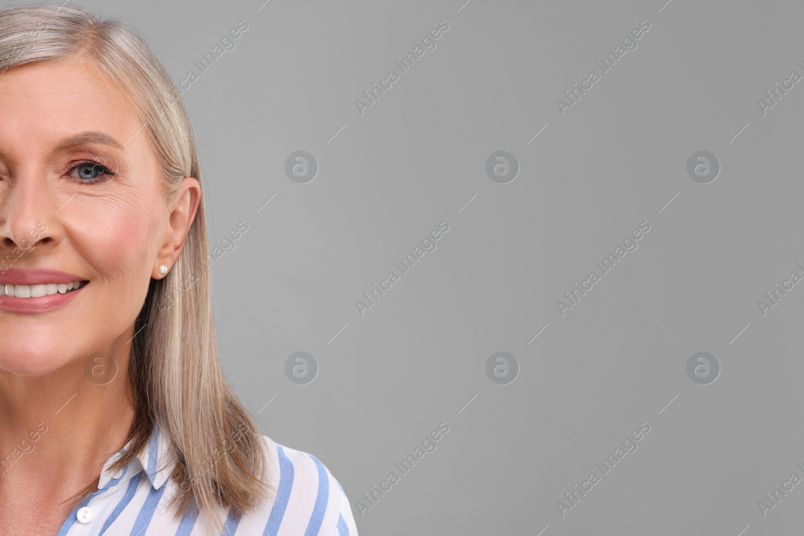 Photo of Portrait of beautiful middle aged woman on light grey background, closeup. Space for text