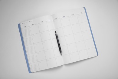 Photo of Open planner and pen on white background, top view