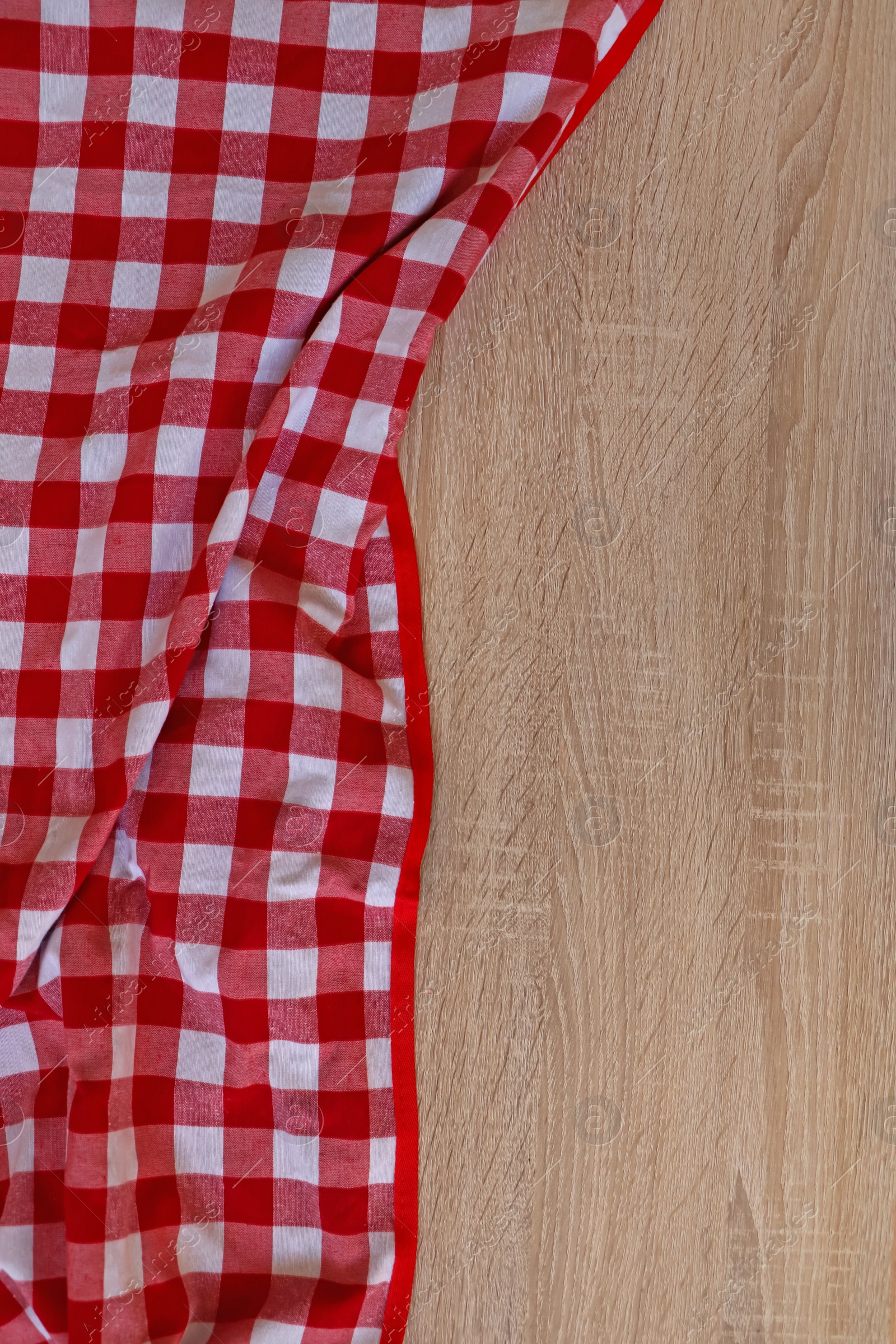 Photo of Checkered picnic cloth on wooden table, top view. Space for text