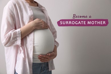 Surrogate mother. Pregnant woman touching her belly on light background, closeup
