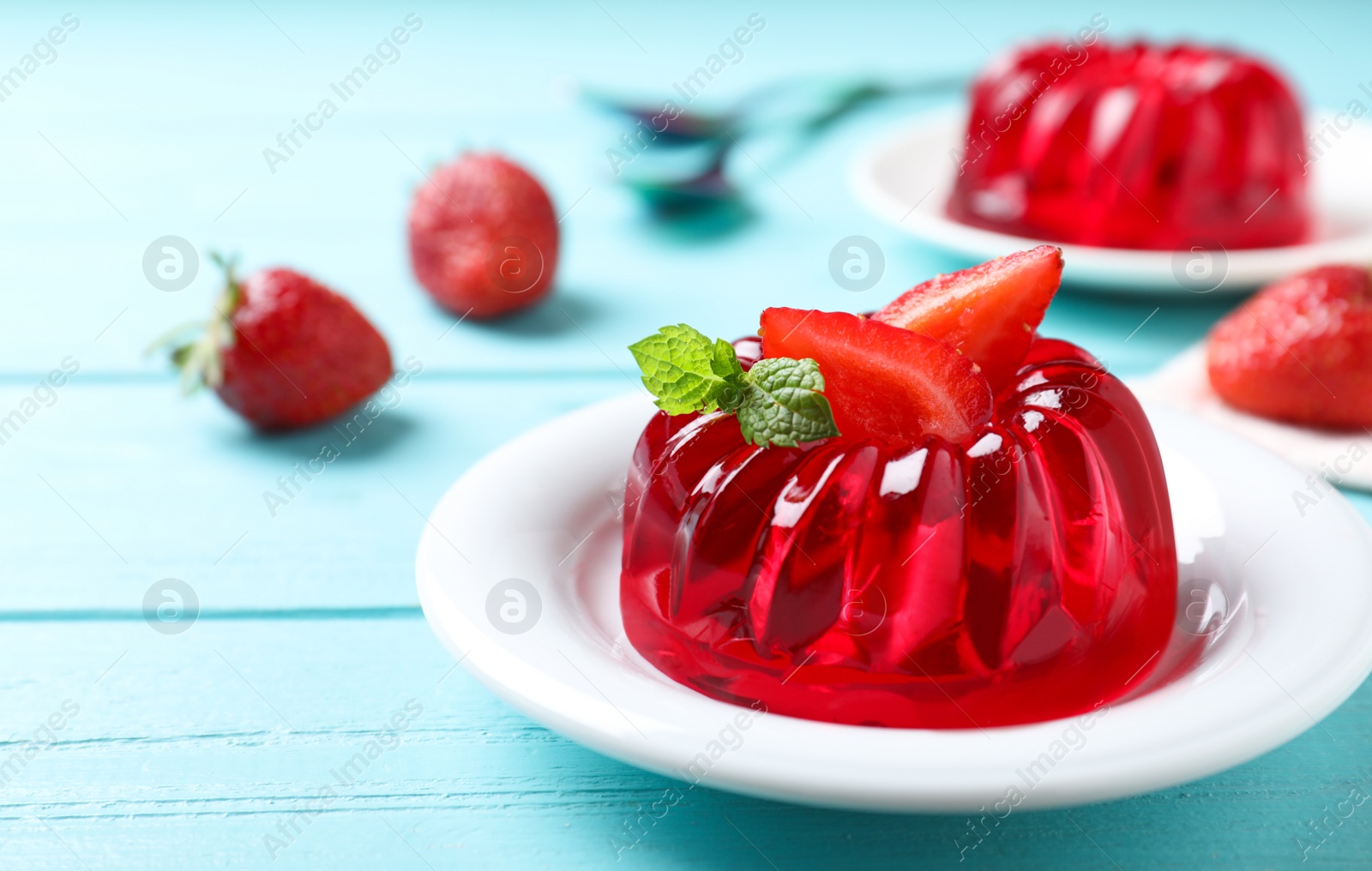 Photo of Delicious red jelly with strawberry and mint on light blue wooden table