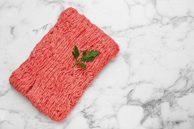 Photo of Raw fresh minced meat with parsley on white marble table, top view. Space for text