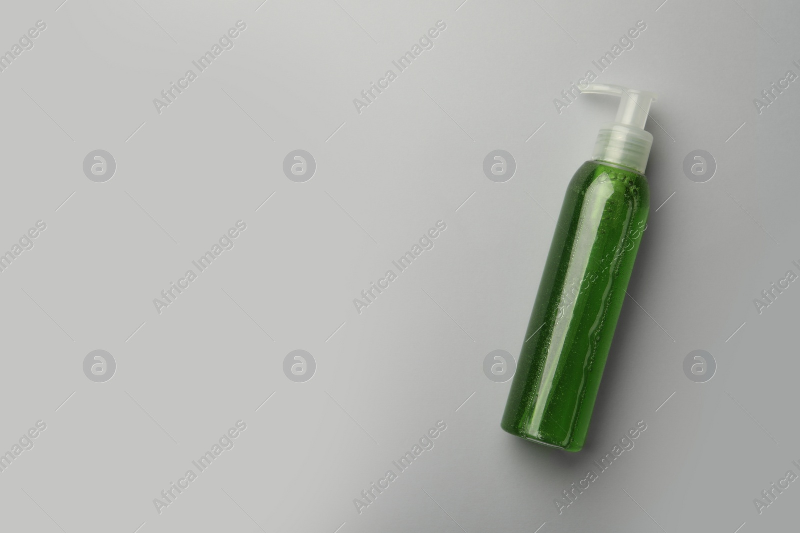 Photo of Bottle of green cosmetic gel on light background, top view. Space for text
