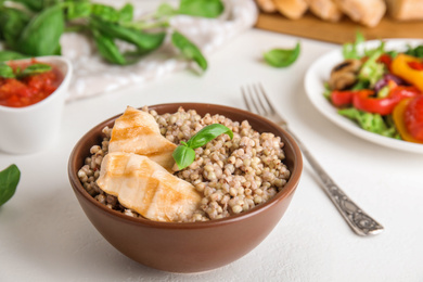 Photo of Tasty buckwheat porridge with meat on white table