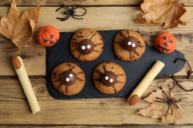 Delicious cookies decorated as monsters on wooden table, flat lay. Halloween treat