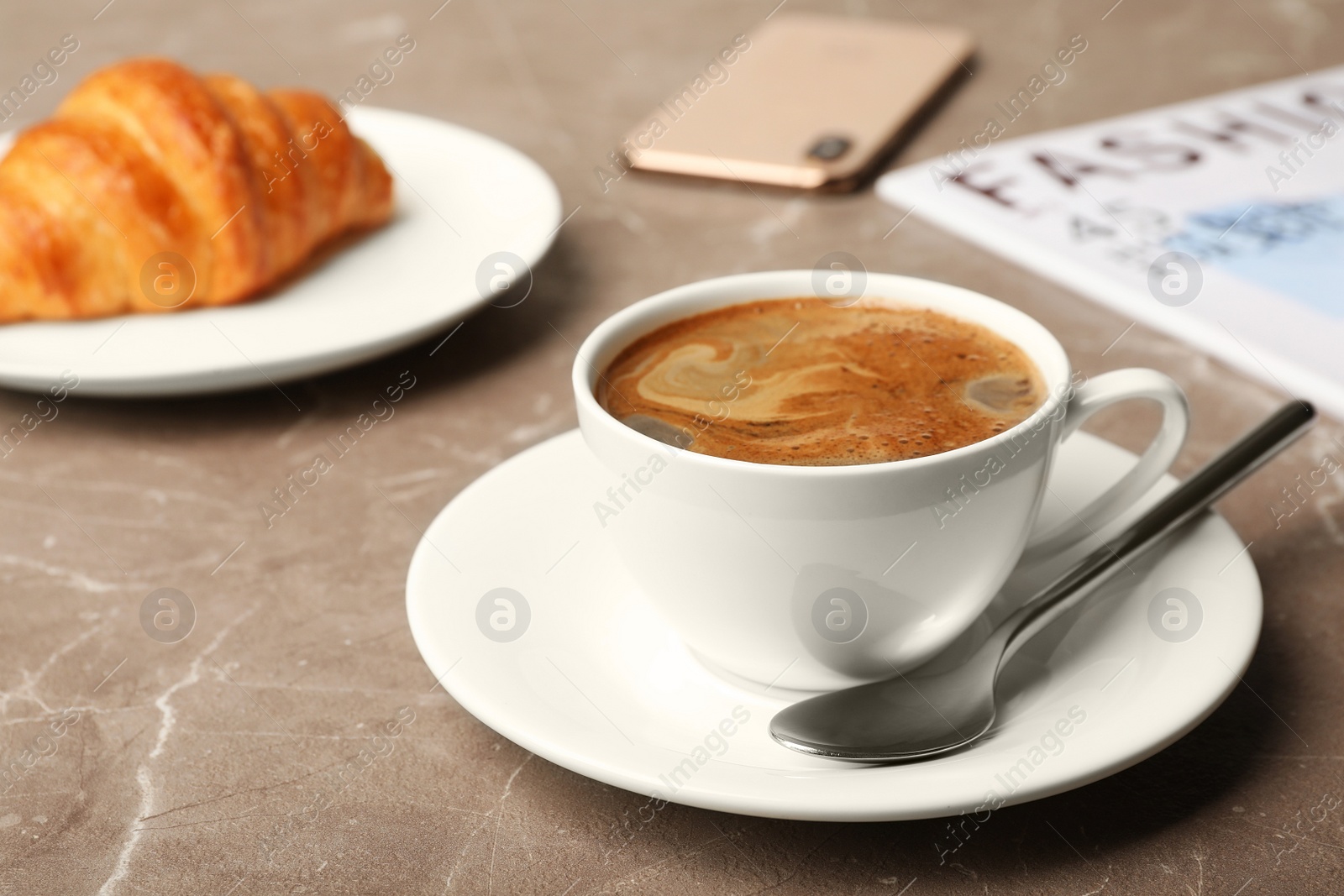 Photo of Cup of tasty aromatic coffee and croissant for breakfast on grey table