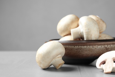 Photo of Fresh champignon mushrooms and plate on table, space for text