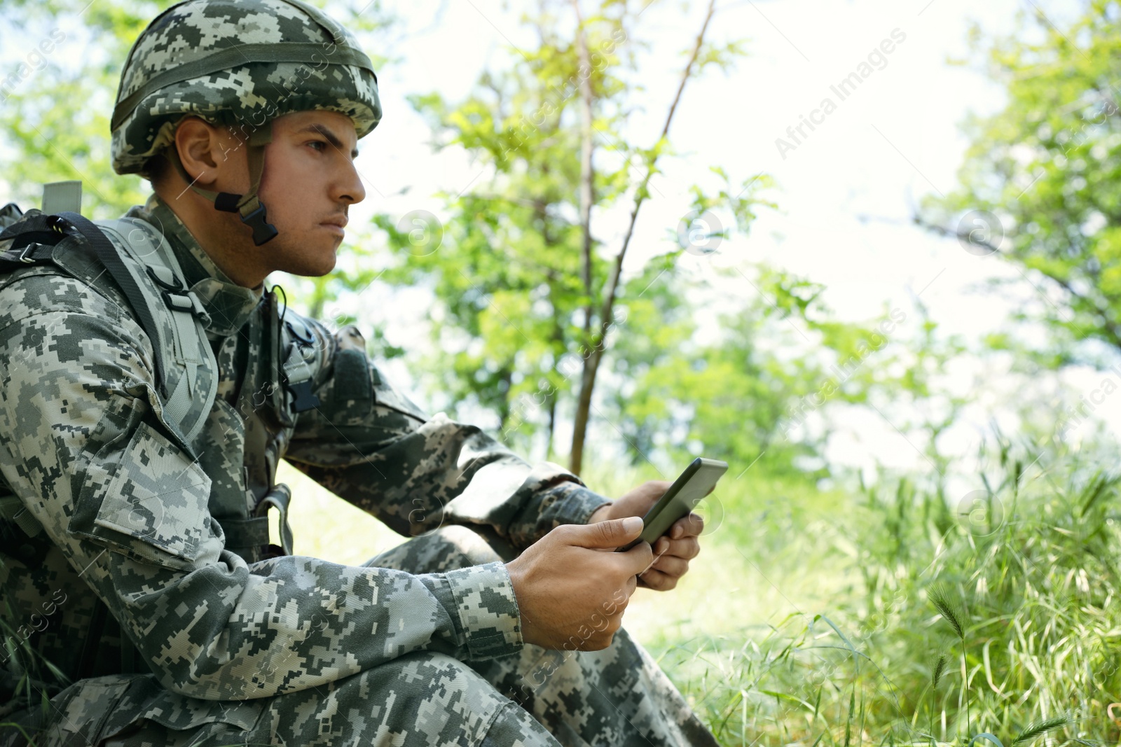 Photo of Soldier with backpack using tablet in forest