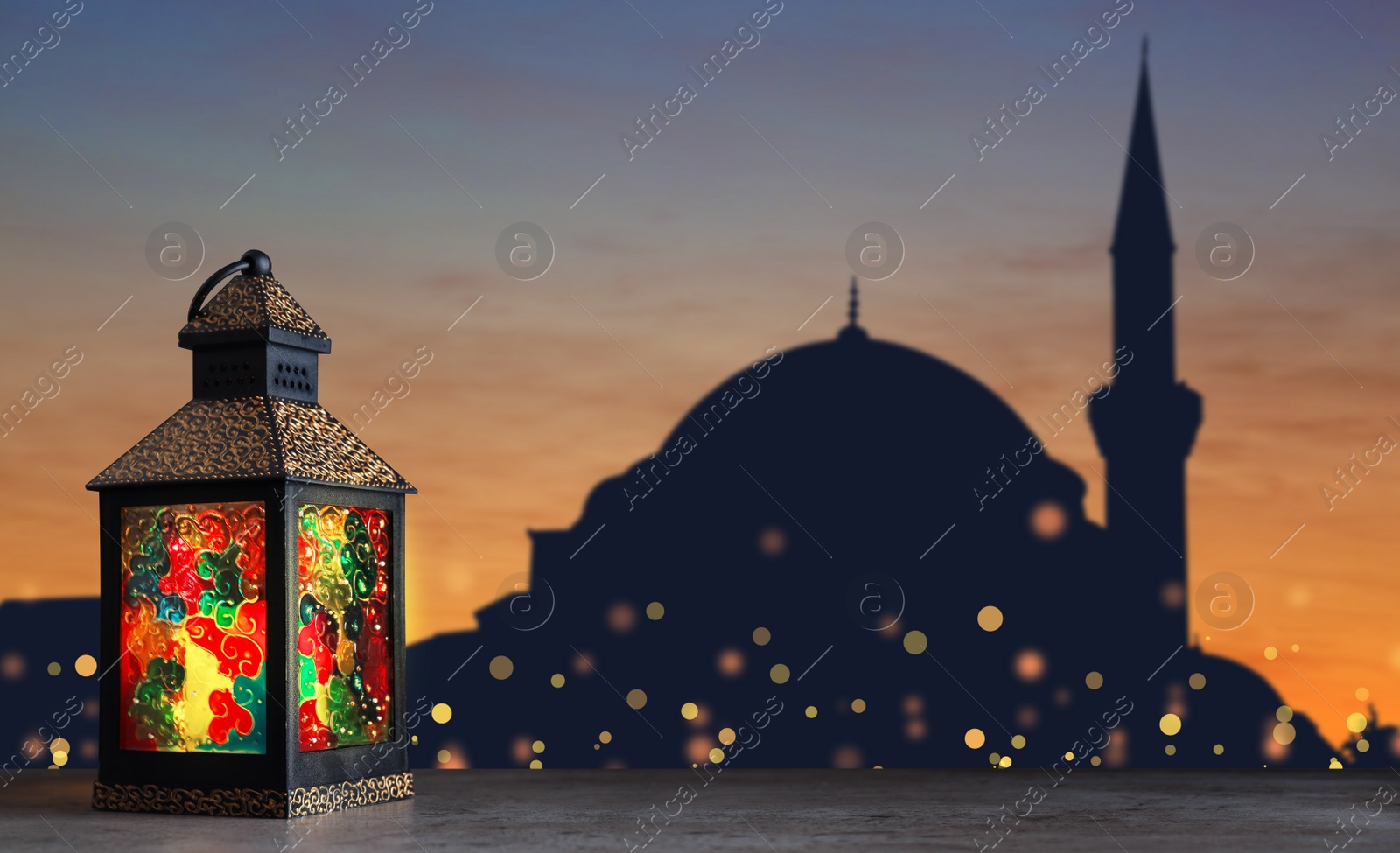 Image of Decorative Arabic lantern on stone surface and silhouette of mosque at sunset on background, space for text