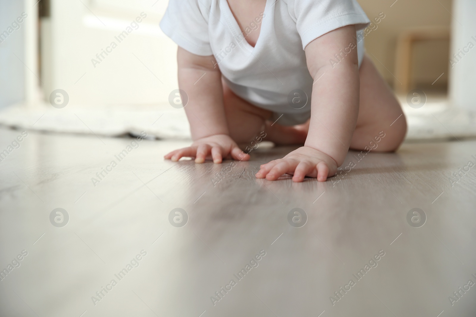 Photo of Cute little baby crawling on floor indoors, closeup with space for text