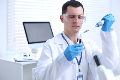 Photo of Scientist dripping sample into test tube in laboratory