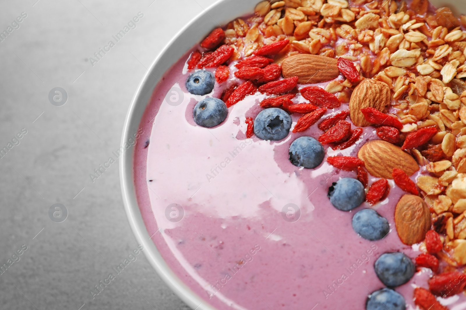 Photo of Smoothie bowl with goji berries on grey table, closeup