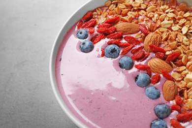 Photo of Smoothie bowl with goji berries on grey table, closeup