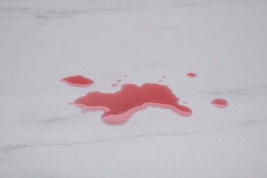 Puddle of red liquid on white marble surface