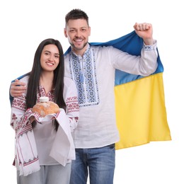 Photo of Happy couple with flag of Ukraine and traditional korovai on white background