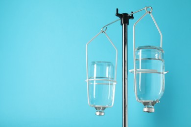 Photo of IV infusion set on pole against light blue background. Space for text