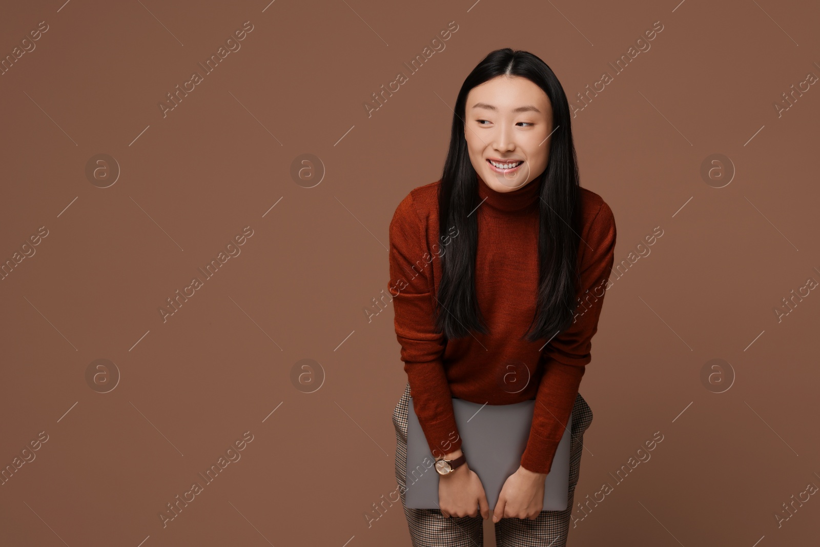 Photo of Portrait of smiling woman with laptop on brown background. Space for text