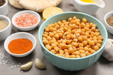 Photo of Delicious chickpeas and different ingredients on light grey table, closeup. Cooking hummus