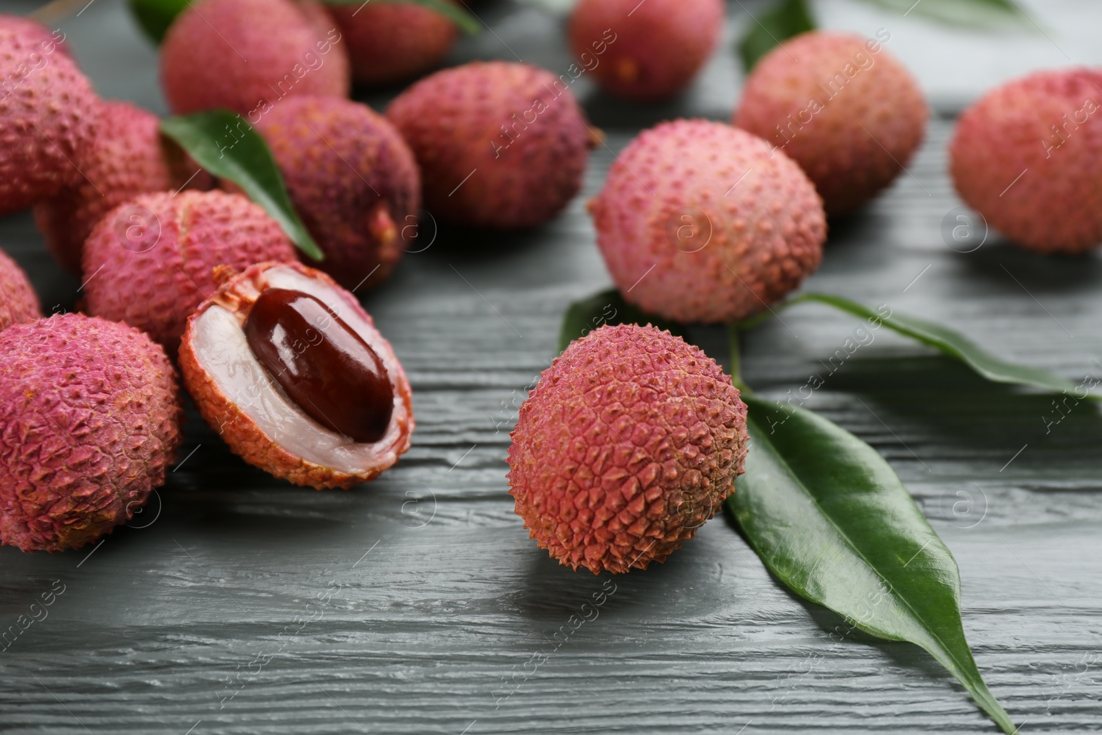 Photo of Fresh ripe lychee fruits on grey wooden table, closeup