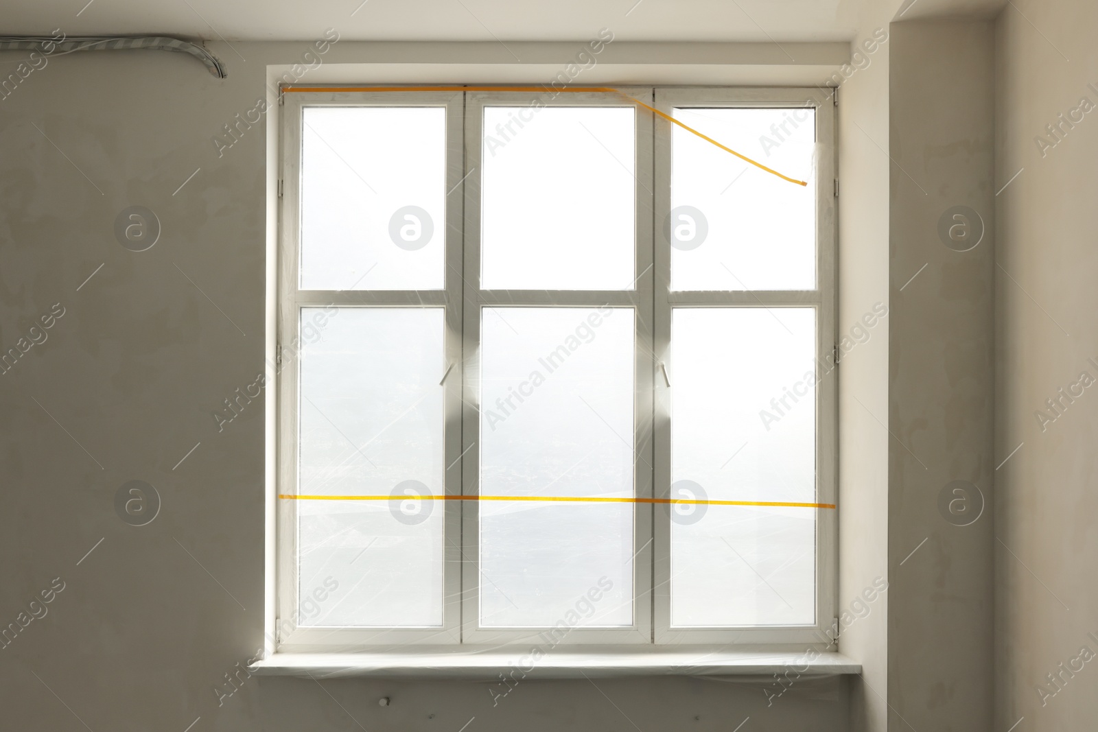 Photo of Window and sill covered by plastic film indoors