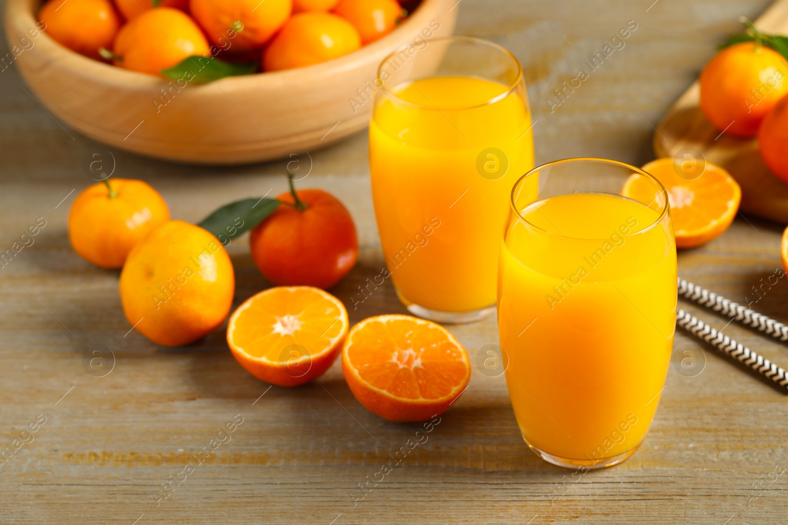 Photo of Glasses of fresh tangerine juice and fruits on wooden table