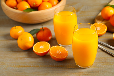 Photo of Glasses of fresh tangerine juice and fruits on wooden table