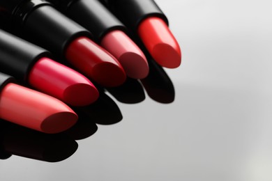 Photo of Many bright lipsticks on light grey background, space for text