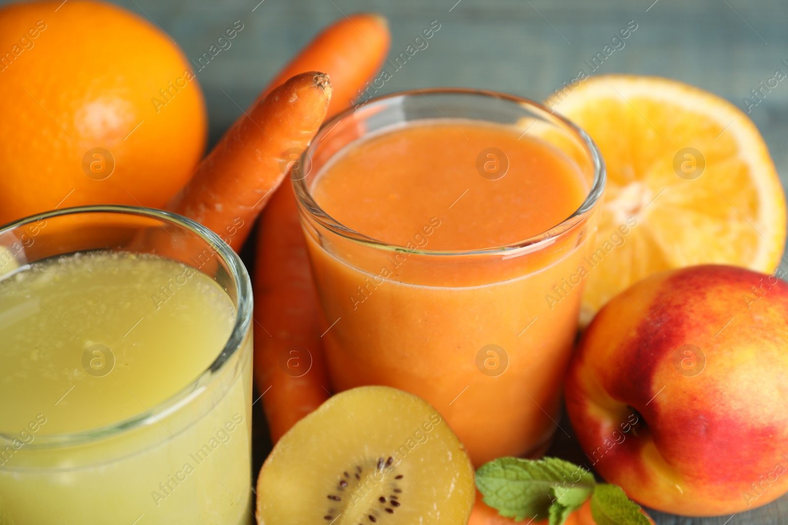 Photo of Glasses of delicious juices and fresh ingredients on table, closeup