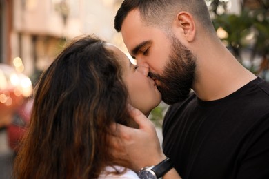 Photo of Happy young couple kissing on city street, closeup