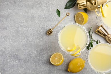 Photo of Delicious bee's knees cocktails and ingredients on light grey table, flat lay. Space for text