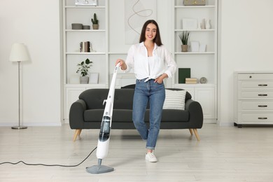 Photo of Happy woman cleaning floor with steam mop at home