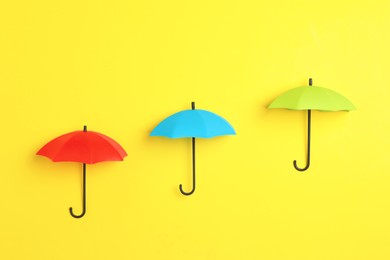 Bright toy umbrellas on yellow background, flat lay